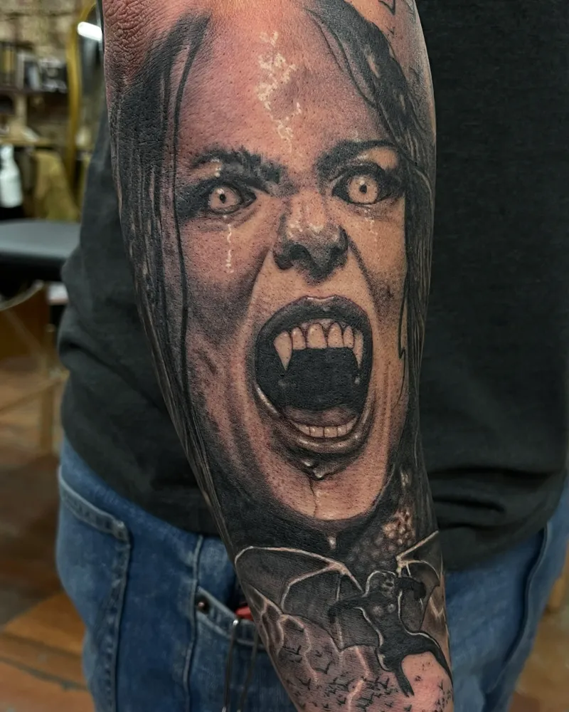 Black and gray tattoo of a screaming vampire woman with fangs and bats