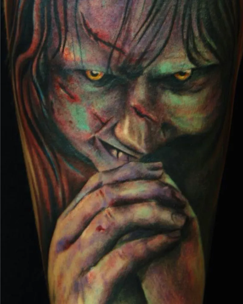 Color close-up tattoo of a snarling green-skinned demon with yellow eyes, fangs, and blood-streaked face