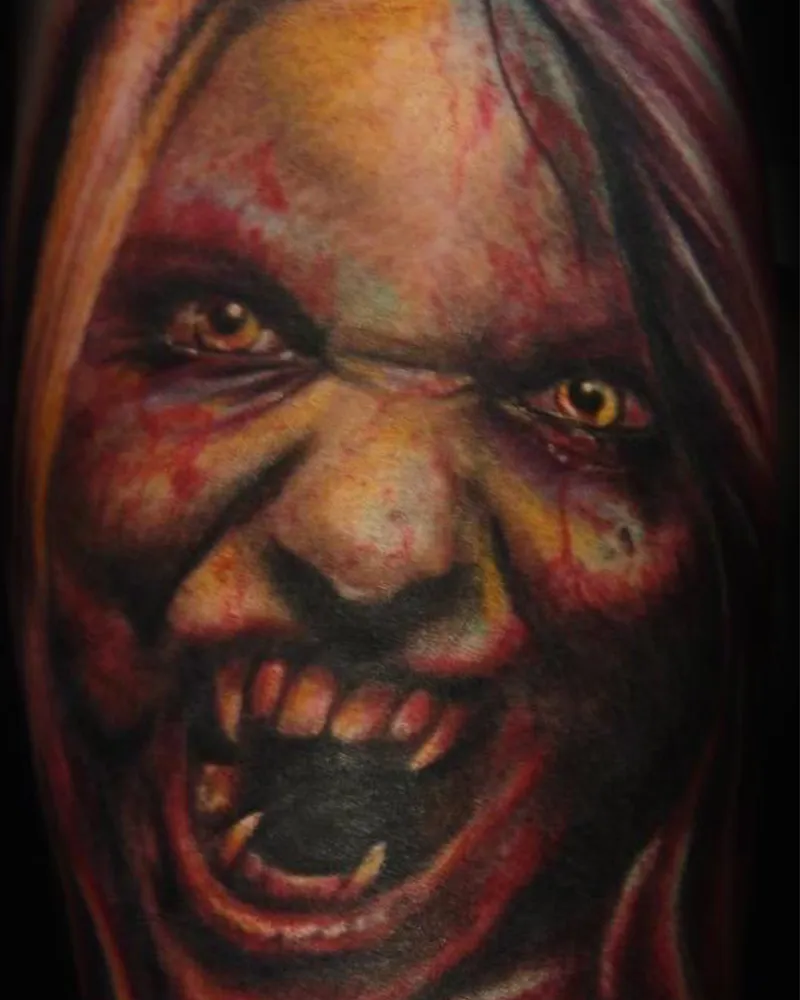 Color close-up tattoo of a screaming demon face with yellow eyes, fangs, and blood spatter, two-tone lighting