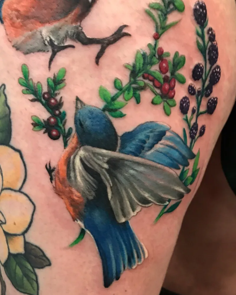 Color tattoo cluster of a small bird in flight alongside branches of cranberries and blackberries