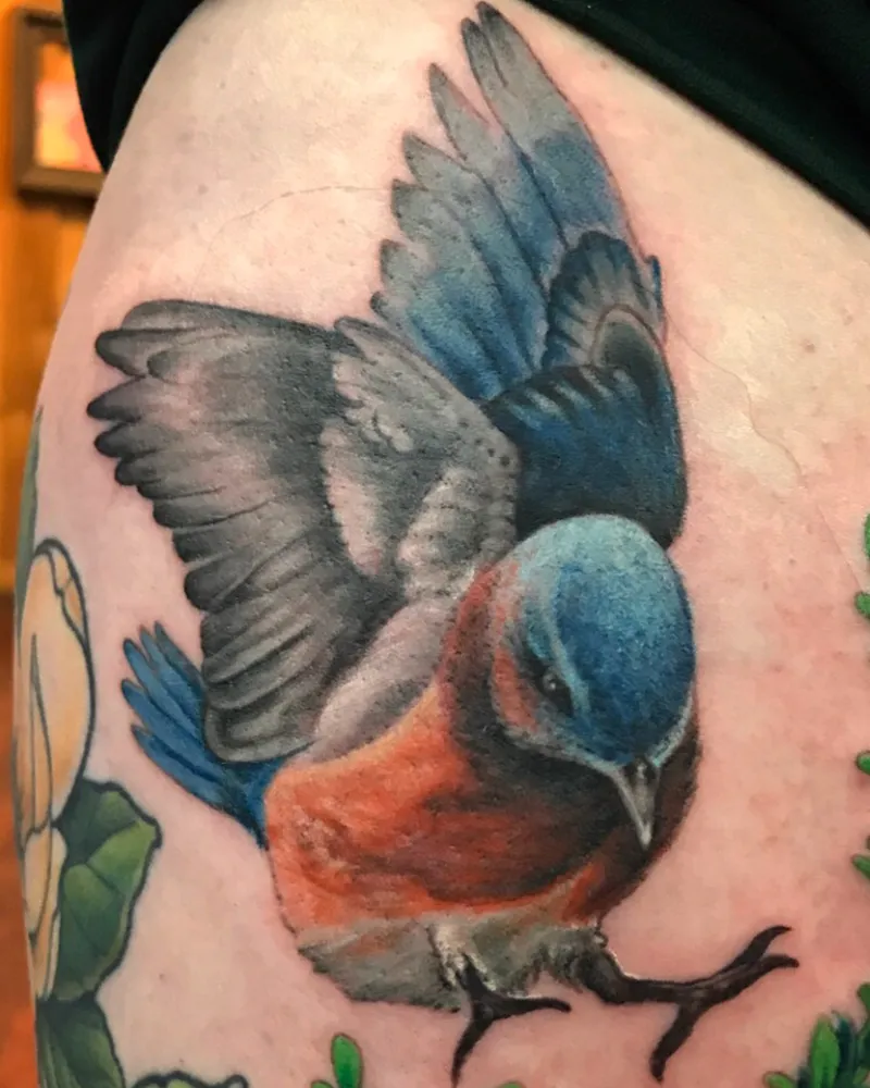 Color realistic Eastern bluebird tattoo with wings spread and an orange chest, on the shoulder