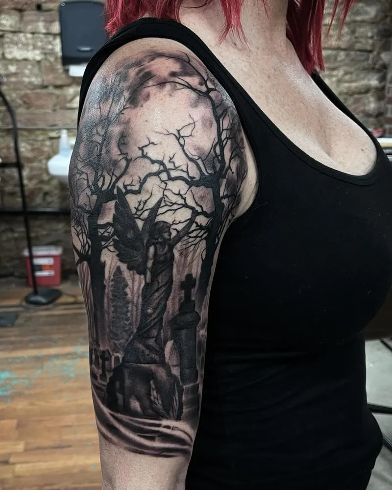 Black and gray half sleeve of a moonlit cemetery with an angel statue, gravestones, and bare trees