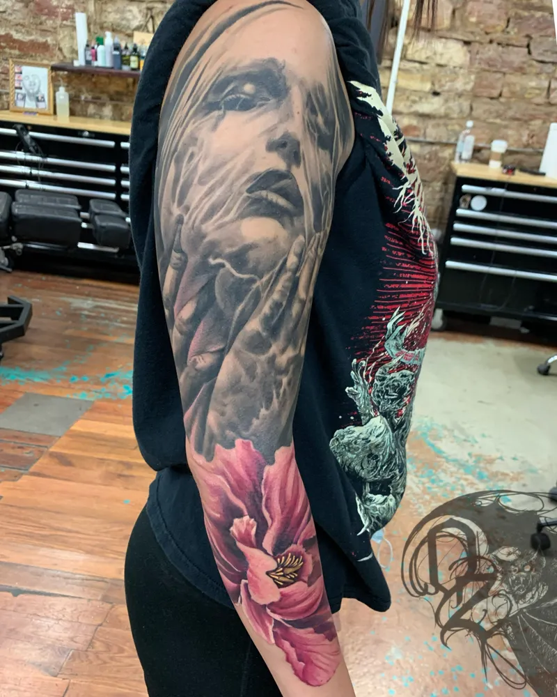 Sleeve pairing a black and gray veiled woman's face held in her hands with a pink peony on the forearm