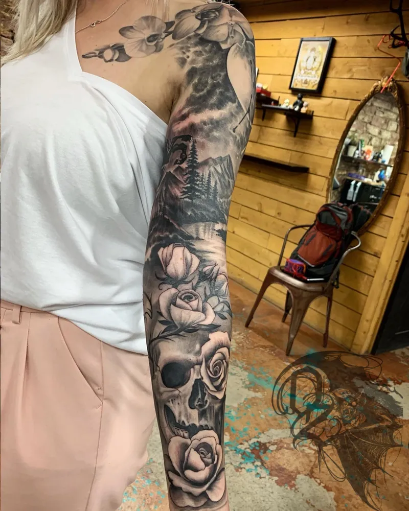 Full sleeve with orchids across the shoulder, a mountain river scene, and roses wrapped around a skull on the forearm