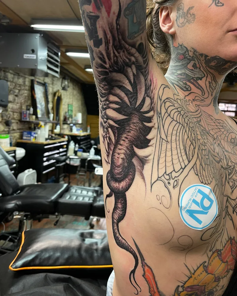 Bioorganic freehand tattoo of a ribbed, tentacled form winding down the inner arm