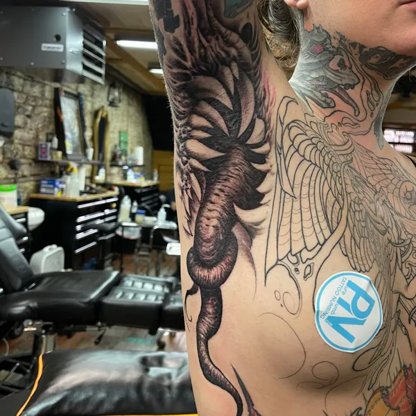 Bioorganic freehand tattoo of a ribbed, tentacled form winding down the inner arm