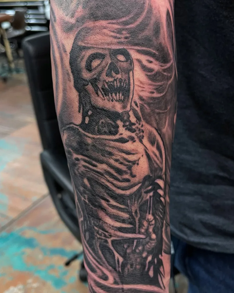 Freehand tattoo of a screaming hooded skeleton on the forearm