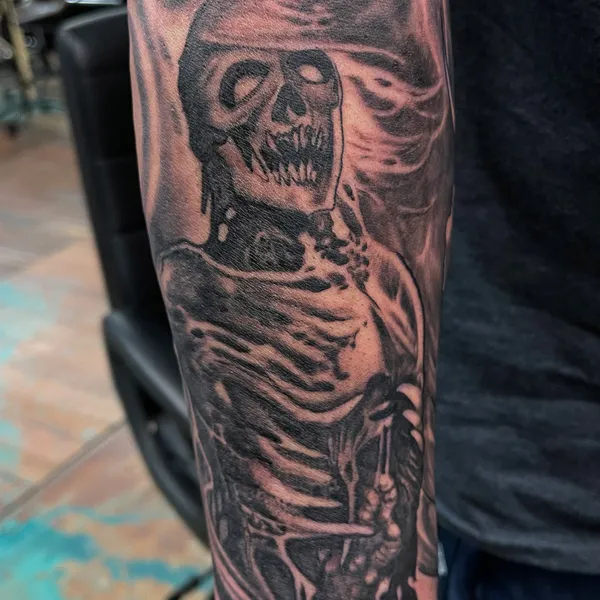 Freehand tattoo of a screaming hooded skeleton on the forearm