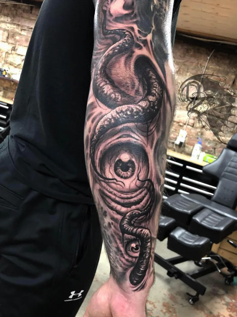 Close-up of a bioorganic freehand tattoo with a coiled serpent and eye on the forearm